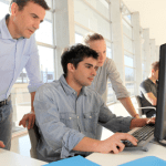 three people looking at a computer screen, providing training