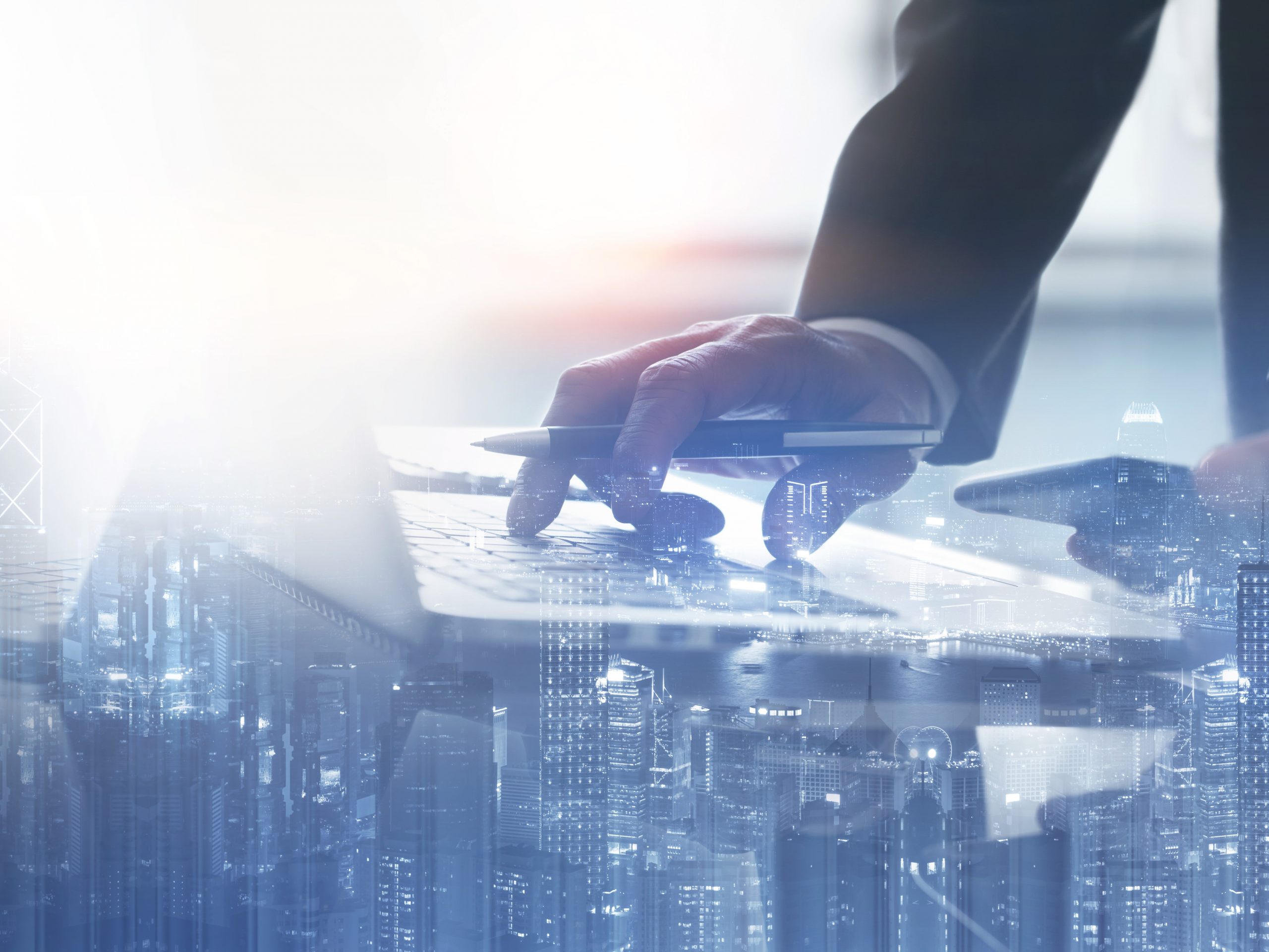 Male hands typing on a laptop with city background