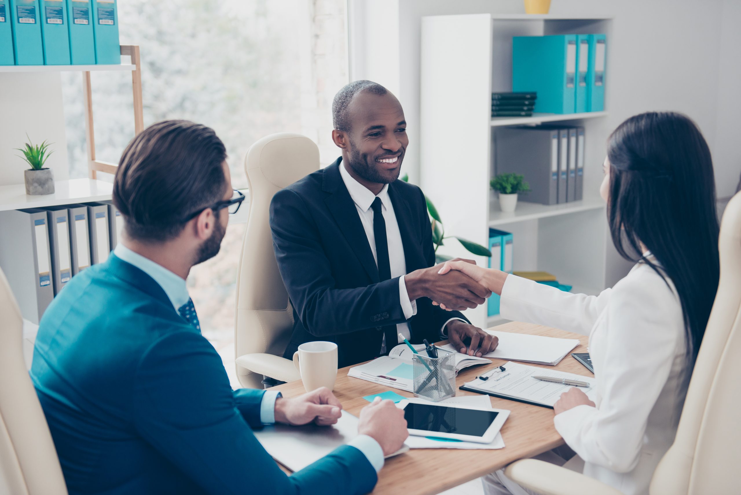 Partners making deal, shaking their hands, sitting in work place